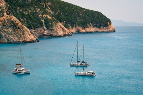 Yacht,In,Turquoise,Sea,By,Mountain,In,Greece
