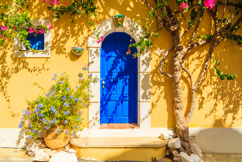 Blue,Door,Of,A,Yellow,Greek,House,Decorated,With,Flowers, Spetses