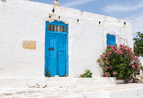 A,Traditional,Whitewashed,House,With,Blue,Doors,And,Windows,Adorned